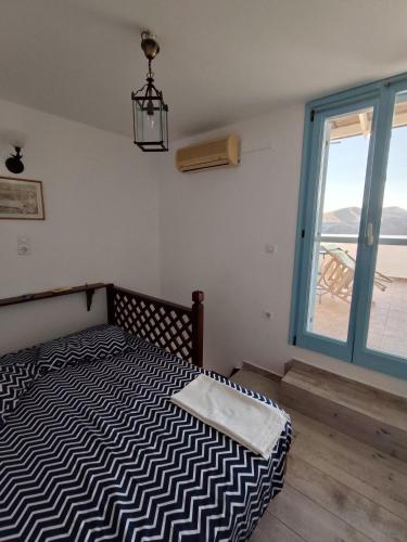a bedroom with a bed with a large window at Asvestoti ciel fish house in Astypalaia