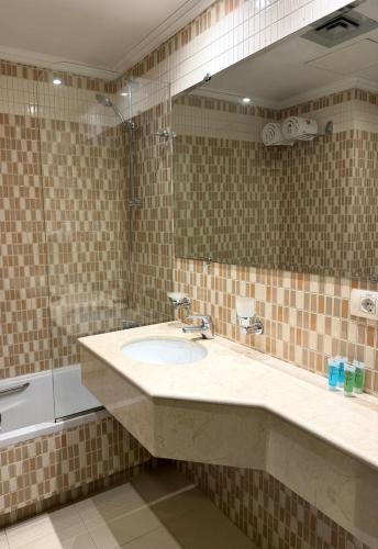 a bathroom with a sink and a mirror and a tub at Ny Suites in Beirut