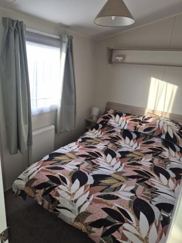 a bedroom with a bed with a colorful comforter at Poppy Caravan in Leysdown-on-Sea