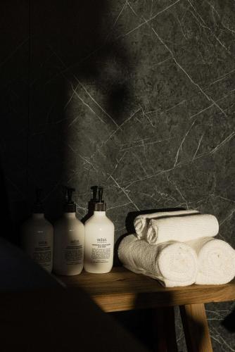 a shelf with four bottles of soap and towels at Heyscape Busselton in Busselton