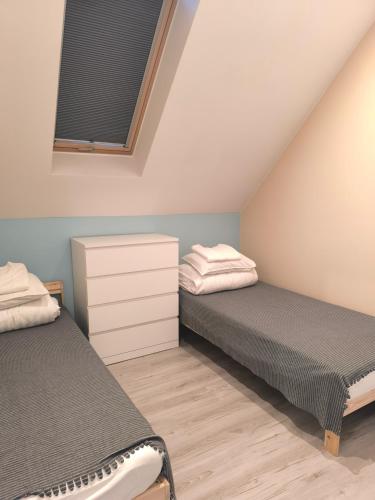 a bedroom with two beds and a window at Apartamenty Wilga - spokojne miejsce z ciszą nocną od 22, całorocznym zewnętrznym wspólnym jacuzzi, sauną i wakacyjnym basenem in Wilga