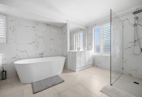 a white bathroom with a tub and a shower at Stunning Waterfront Escape in Gold Coast