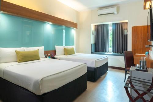 a hotel room with two beds and a desk and window at Microtel by Wyndham UP Technohub in Manila