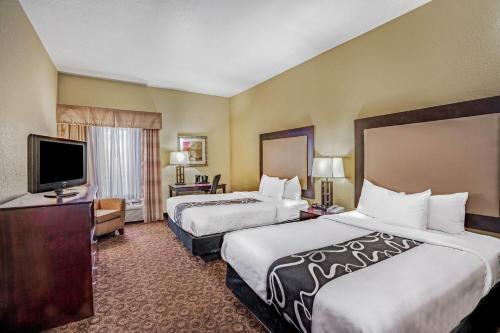 a hotel room with two beds and a flat screen tv at La Quinta by Wyndham Vicksburg in Vicksburg