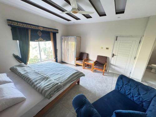 a bedroom with a bed and a couch and a window at EmberGuestHouse in Abbottabad