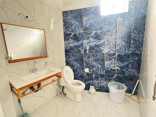 a bathroom with a toilet and a sink and a mirror at EmberGuestHouse in Abbottabad