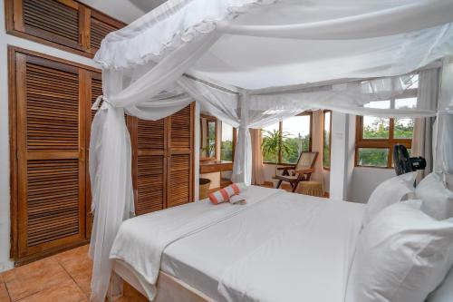 a bedroom with a white bed with a canopy at Hewani a bright & airy 1 BR apartment with an ocean view & pool in Kilifi