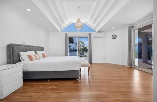 a white bedroom with a bed and a large window at Stunning Waterfront Escape in Gold Coast