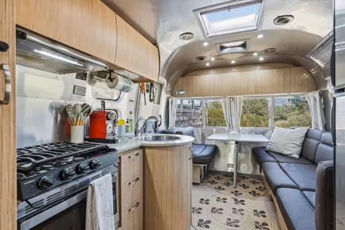 an rv kitchen with a stove and a couch at Yosemite's Best Glamping Airstream Experience! in Coarsegold