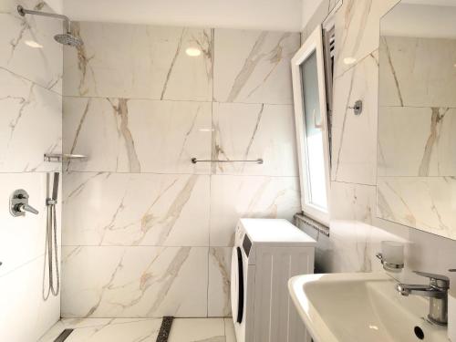 a white bathroom with a shower and a sink at Enjoy Shkodra Apartment in Shkodër