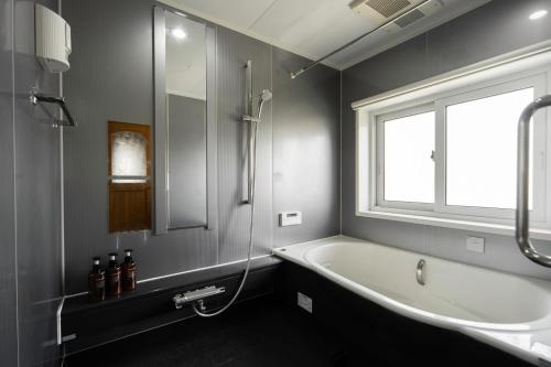 a bathroom with a bath tub and a window at Nagano Villa 翠 in Nagano