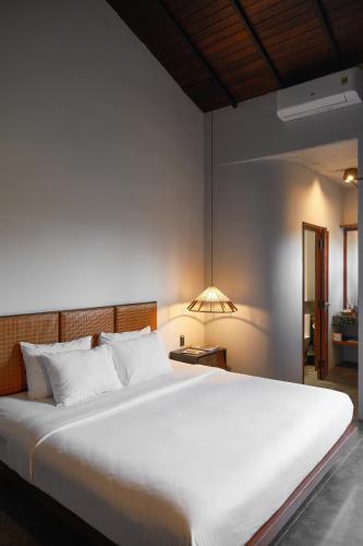 a bedroom with a large white bed and a lamp at De Hué in Hue
