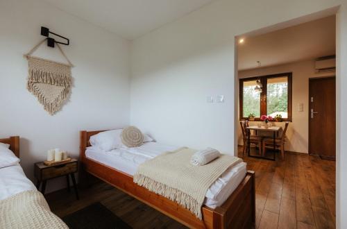 a bedroom with two beds and a dining room with a table at Leśne Apartamenty in Bobolice