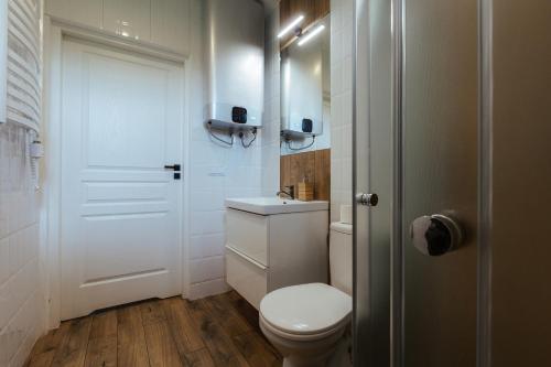 a white bathroom with a toilet and a sink at Leśne Apartamenty in Bobolice
