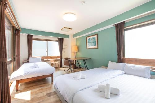a hotel room with two beds and a desk at Mitte Misono Apartments in Sapporo
