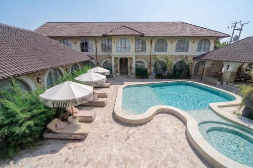 a woman sitting on chairs next to a swimming pool at Maison Boheme Modern Apartment & Villa with Pool in Sanur in Sanur