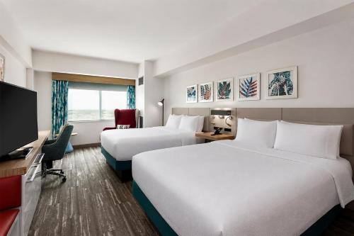 a hotel room with two beds and a flat screen tv at Hilton Garden Inn Ithaca in Ithaca