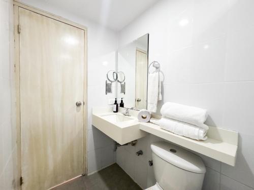 a white bathroom with a toilet and a sink at Casa Helena Hotel Centro Historico in Cartagena de Indias