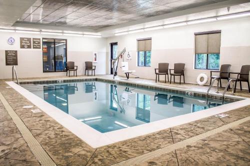 a swimming pool with chairs and tables in a building at Comfort Suites Hartville-North Canton in Uniontown