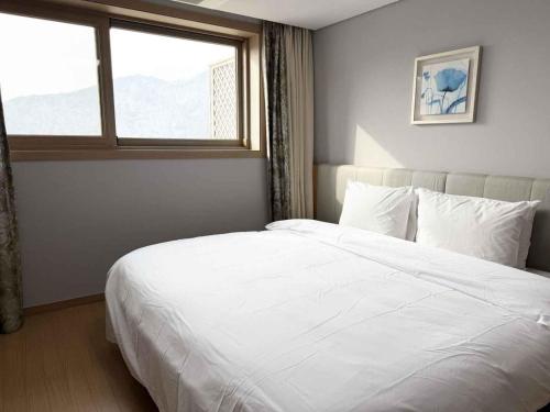 a bedroom with a large white bed with a window at STX Resort in Mungyeong