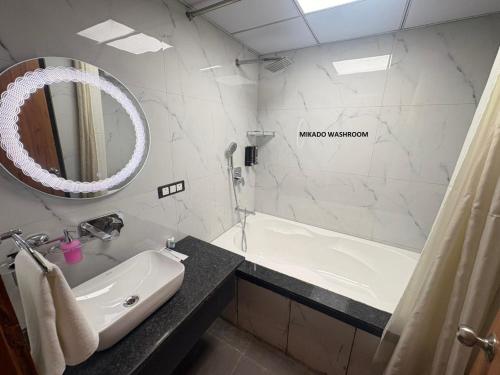 a bathroom with a sink and a tub and a mirror at Hotel Mikado Palace in Gurgaon