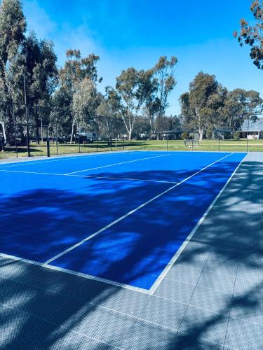 a blue tennis court with trees in the background at Ingenia Holidays Murray Bend in Koonoomoo