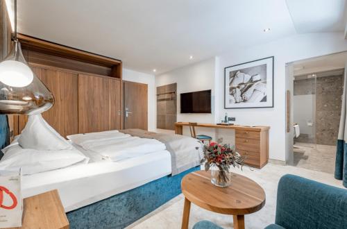 a hotel room with a bed and a table and a couch at Superior Hotel Edelweiss in Obertauern
