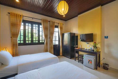 a bedroom with two beds and a desk and a television at Old Lane Homestay in Hoi An