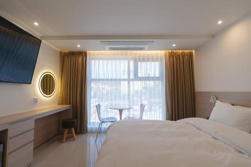 ein Hotelzimmer mit einem Bett, einem Tisch und einem Fenster in der Unterkunft MH Hotel 2 in Jeonju