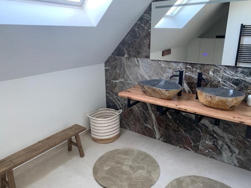 a bathroom with two sinks and a bench and a skylight at Villa Houtave in Zuienkerke