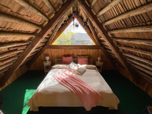 a bed in a attic room with a window at Gaismas klēts in Upmaļciems