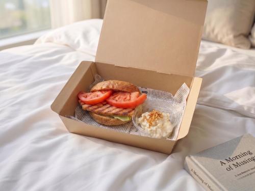 a box with a sandwich in it on a bed at Play!! RESI STAY in Kyoto