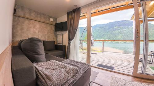 a living room with a couch and a large window at Seecamping & Pension Mentl in Landskron