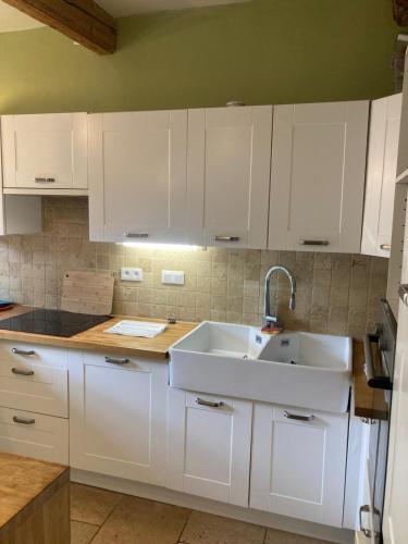 a kitchen with white cabinets and a sink at Charmant duplex 8 couchages 75 m2, terrasse 12 m2 dans village typique héraultais in Tourbes