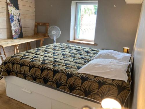 a bed in a bedroom with a fan and a window at Charmant duplex 8 couchages 75 m2, terrasse 12 m2 dans village typique héraultais in Tourbes