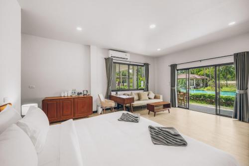a bedroom with a bed and a desk and a couch at Anahata Resort in Lipa Noi