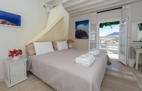 a bedroom with a white bed with a balcony at Petali Village Hotel in Apollonia