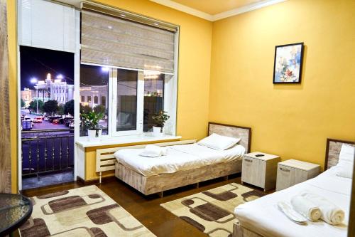 a room with two beds and a large window at Dilbar Guest House in Samarkand