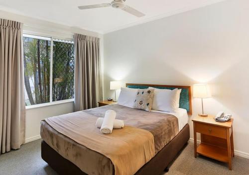 a bedroom with a large bed with a window at Ivory Palms Resort Noosa in Noosaville