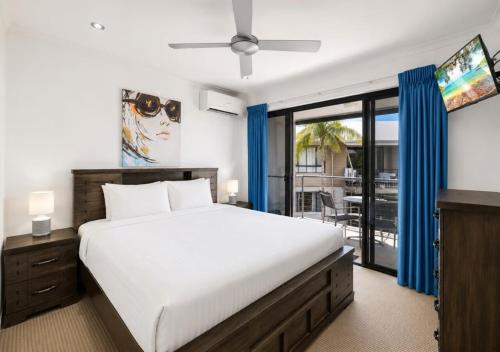 a bedroom with a large white bed and a tv at Ivory Palms Resort Noosa in Noosaville