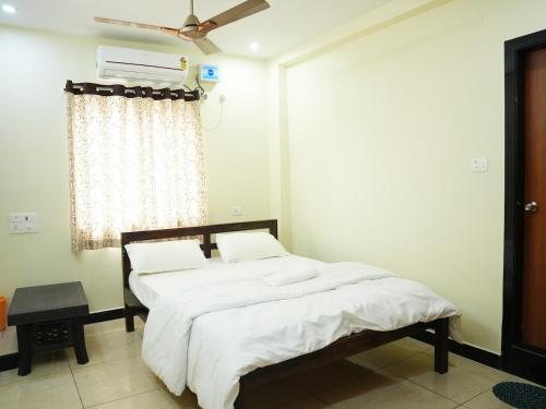 a bedroom with a bed with white sheets and a window at Hotel Brinda in Kākināda