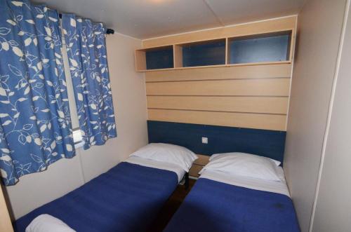 two beds in a small room with blue curtains at Camping Village Città di Milano in Milan