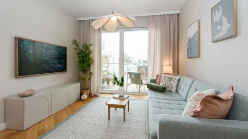 a living room with a blue couch and a large window at Baltic Pine by Pino Resort in Gdańsk