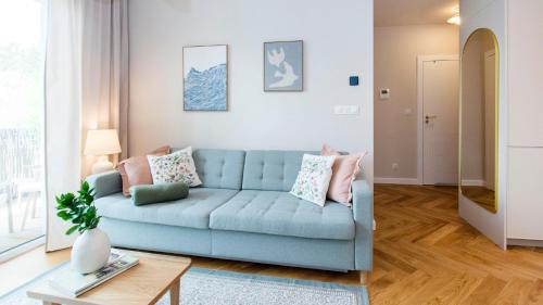 a living room with a blue couch and a table at Baltic Pine by Pino Resort in Gdańsk