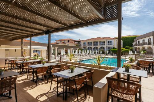 an outdoor patio with tables and chairs and a swimming pool at Diana Palace Hotel Zakynthos in Argassi
