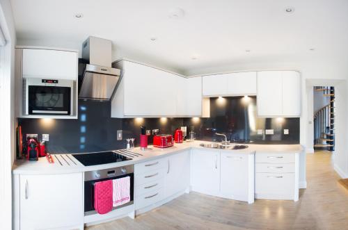 una cucina con armadi bianchi e piano cottura di Glenmoriston Town House Apartments a Inverness