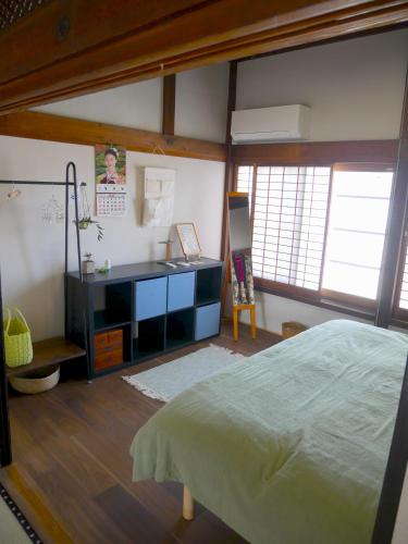 a bedroom with a bed and a desk and windows at ましこのま- 明治の建物をリノベした街中ローカルステイ in Mashiko