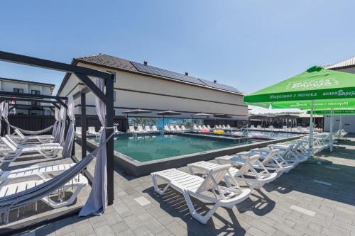 a swimming pool with lounge chairs and a green umbrella at Fenix in Solotvyno