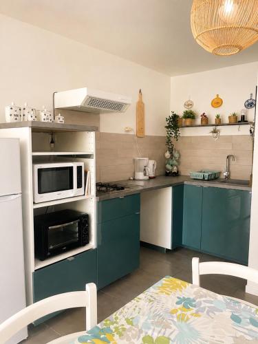 a kitchen with blue cabinets and a white microwave at L'Oléastre en Luberon in Grambois