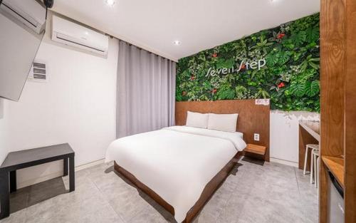 a bedroom with a bed and a painting on the wall at Hotel Seven Step in Incheon